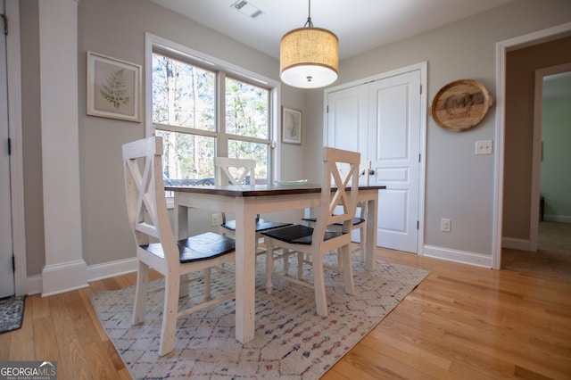 dining room featuring baseboards, visible vents, and light wood finished floors