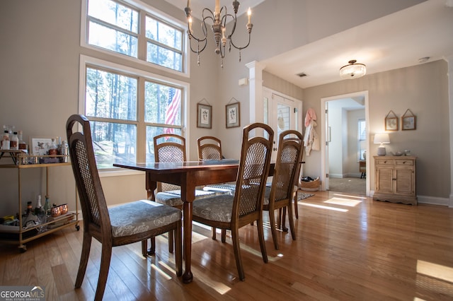 dining area featuring decorative columns, visible vents, a chandelier, and hardwood / wood-style flooring