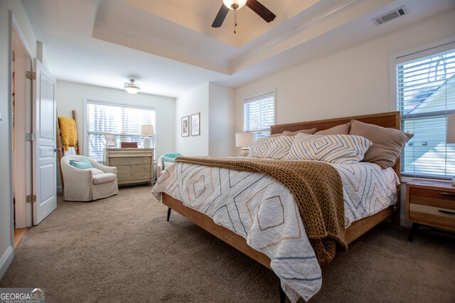 carpeted bedroom featuring ceiling fan and a tray ceiling