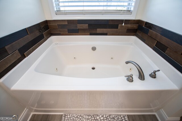 bathroom with a tub to relax in and a healthy amount of sunlight