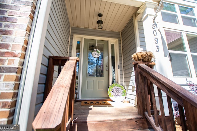 view of exterior entry with brick siding and covered porch