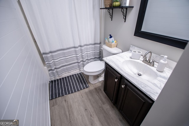 bathroom with a shower with shower curtain, toilet, wood finished floors, and vanity