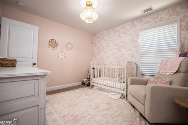 bedroom featuring a crib, baseboards, visible vents, and wallpapered walls