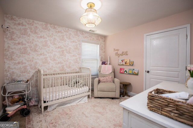 bedroom featuring light carpet and a nursery area