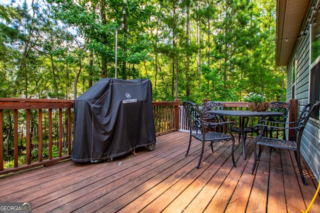 wooden terrace with outdoor dining space and area for grilling