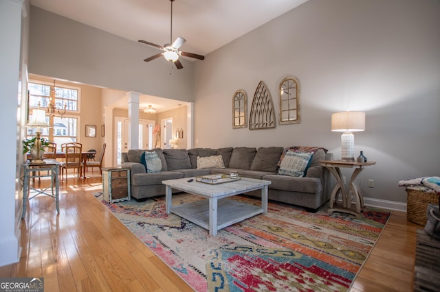 living room featuring decorative columns, high vaulted ceiling, hardwood / wood-style floors, and a ceiling fan