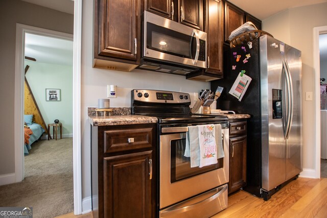 kitchen featuring stainless steel appliances, light wood-type flooring, and dark brown cabinets