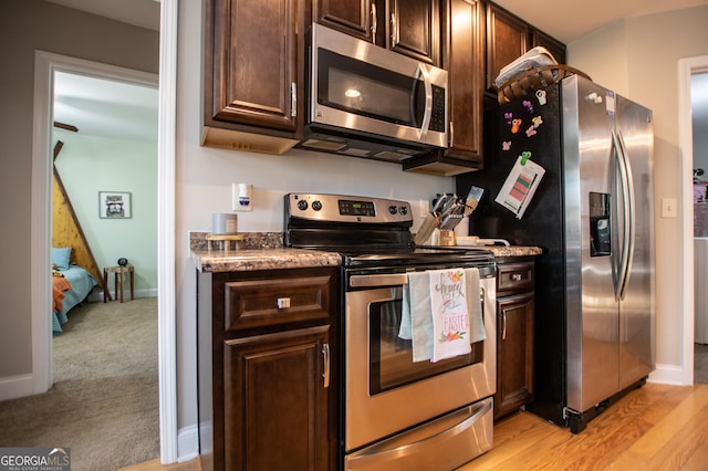 kitchen featuring light wood finished floors, dark brown cabinets, stainless steel appliances, and baseboards