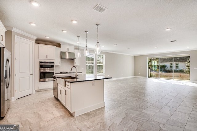 kitchen featuring hanging light fixtures, stainless steel appliances, white cabinets, an island with sink, and ornamental molding