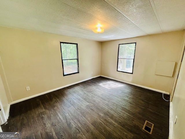 empty room featuring a textured ceiling and dark wood-type flooring