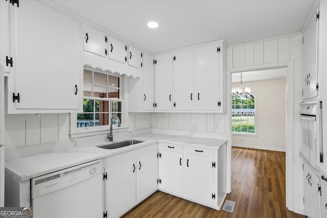 kitchen featuring white cabinetry, dark wood-type flooring, white appliances, an inviting chandelier, and sink