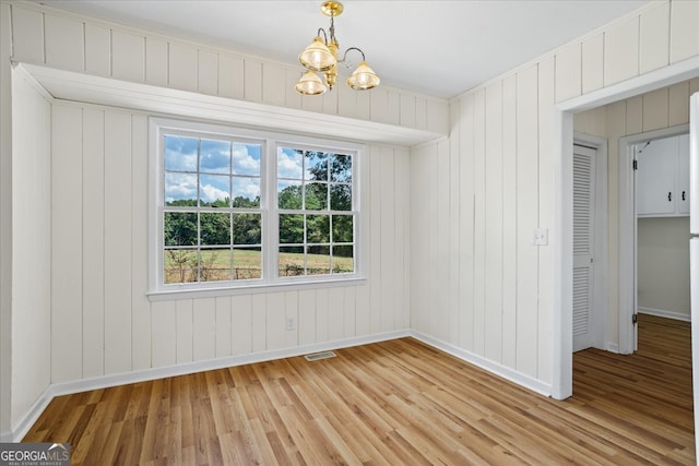 unfurnished dining area featuring an inviting chandelier and light wood-type flooring