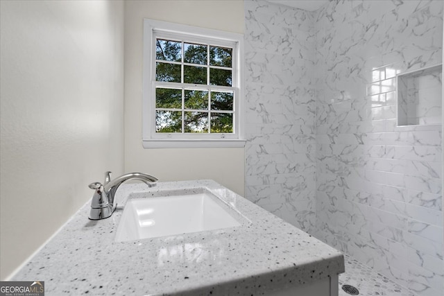 bathroom featuring tiled shower and vanity