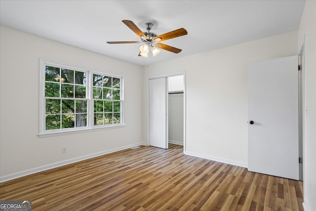 unfurnished bedroom featuring ceiling fan, a closet, and hardwood / wood-style flooring