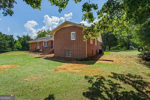 view of side of property with central AC unit and a lawn