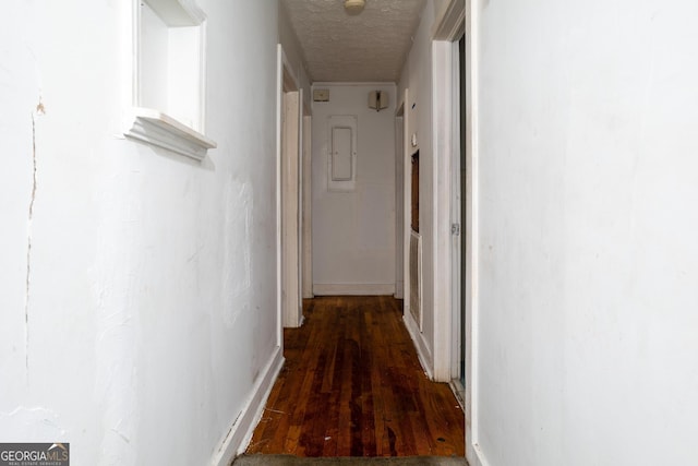 corridor with a textured ceiling, electric panel, and dark hardwood / wood-style flooring