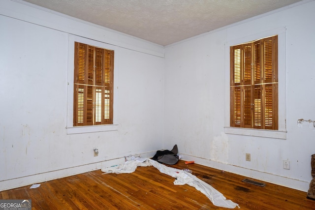 spare room featuring ornamental molding, a textured ceiling, hardwood / wood-style flooring, and a wealth of natural light