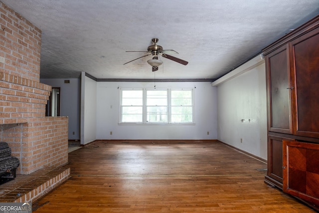 unfurnished living room with a textured ceiling, ceiling fan, a brick fireplace, and hardwood / wood-style flooring