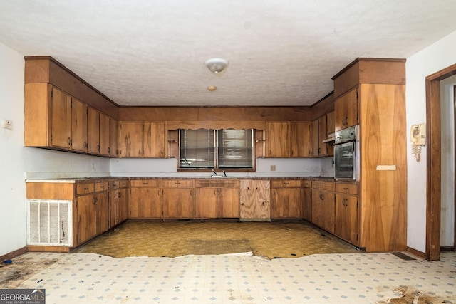 kitchen with black oven, sink, and a textured ceiling