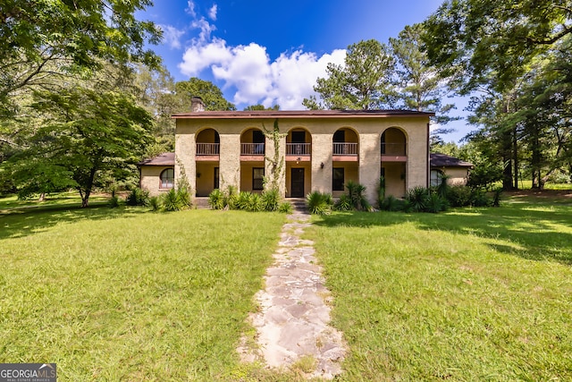 mediterranean / spanish-style house with a balcony and a front lawn