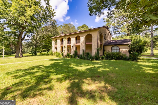 view of front of property featuring a balcony and a front lawn