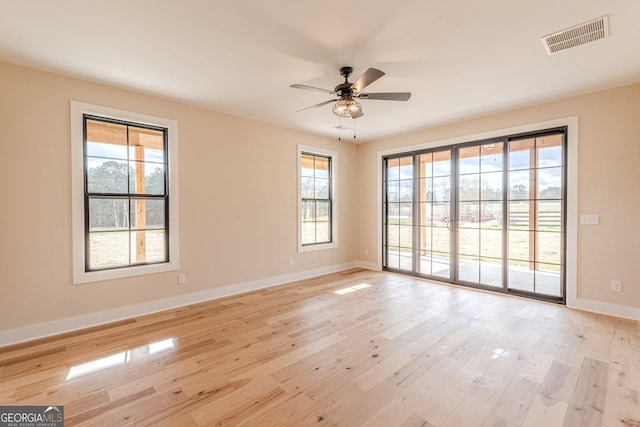 spare room featuring light hardwood / wood-style floors, ceiling fan, and plenty of natural light