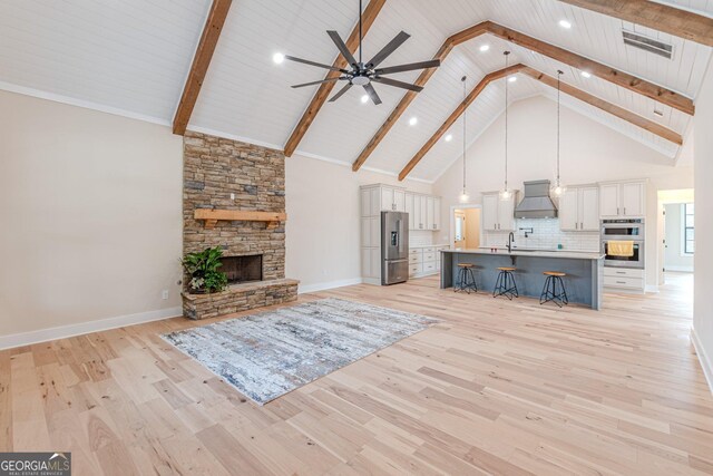 unfurnished living room with wood ceiling, high vaulted ceiling, light hardwood / wood-style floors, and a fireplace