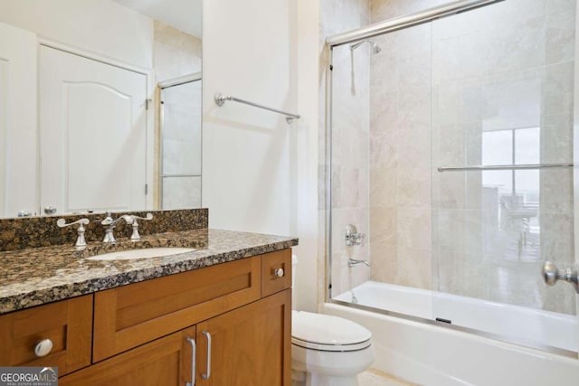 full bathroom featuring toilet, combined bath / shower with glass door, and vanity