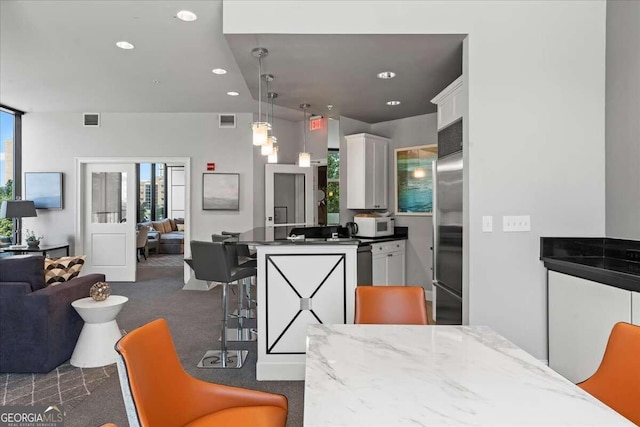 kitchen featuring dark carpet, stainless steel appliances, white cabinets, and a breakfast bar area