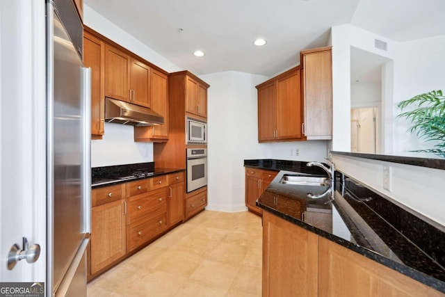 kitchen with appliances with stainless steel finishes, sink, and dark stone countertops