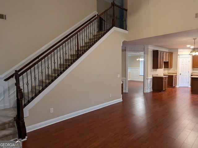 unfurnished living room with an inviting chandelier, a high ceiling, and dark hardwood / wood-style flooring