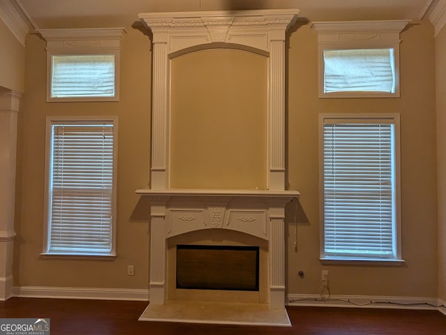 unfurnished living room with dark wood-type flooring, plenty of natural light, ornamental molding, and ornate columns