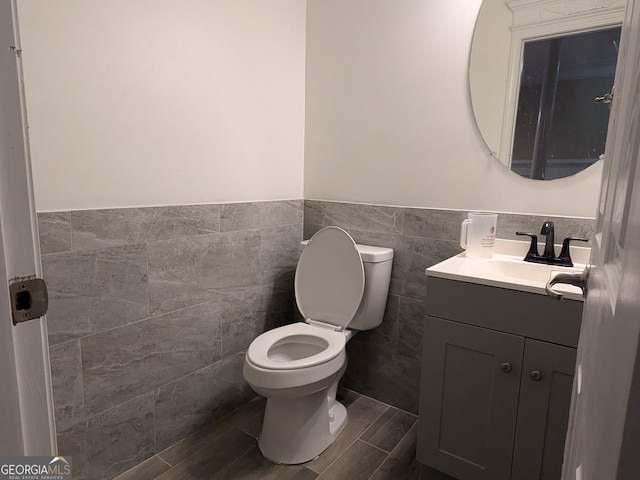 bathroom featuring vanity, tile walls, toilet, and wood-type flooring