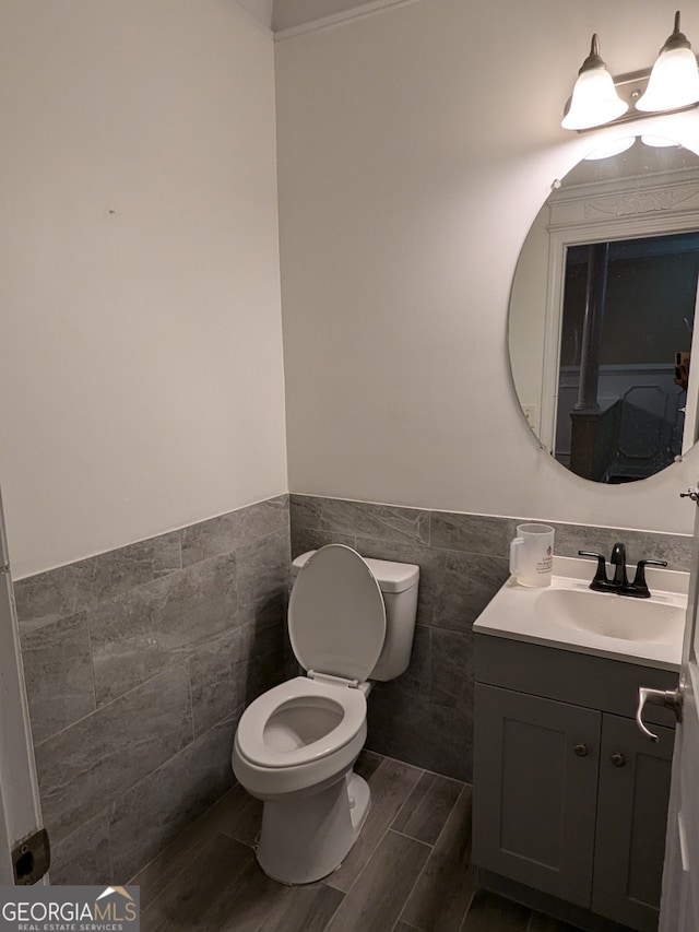 bathroom featuring tile walls, wood-type flooring, vanity, and toilet