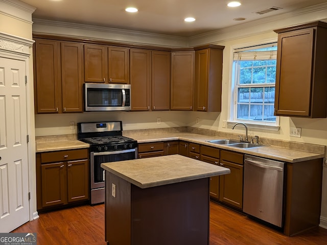 kitchen with sink, dark wood-type flooring, appliances with stainless steel finishes, a center island, and crown molding