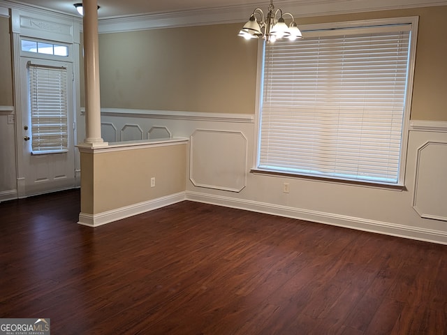 empty room featuring ornate columns, crown molding, a notable chandelier, and dark wood-type flooring