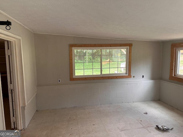 unfurnished room with a textured ceiling and vaulted ceiling