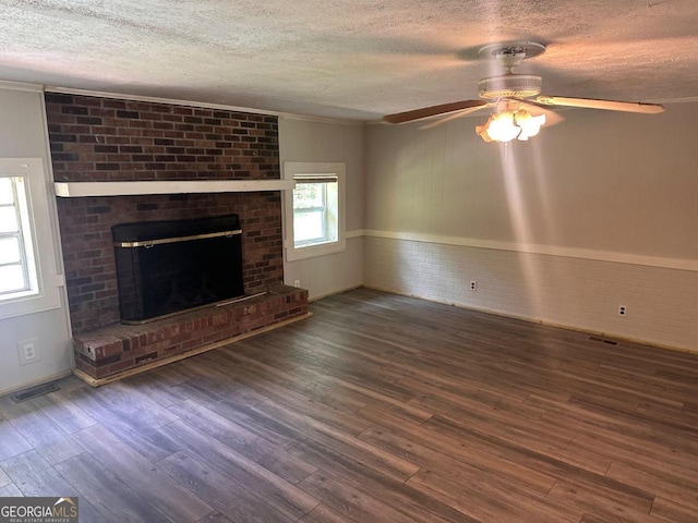 unfurnished living room featuring ceiling fan, a fireplace, a textured ceiling, and dark hardwood / wood-style flooring