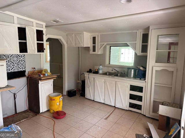 kitchen with sink, white cabinetry, a textured ceiling, and light tile patterned floors