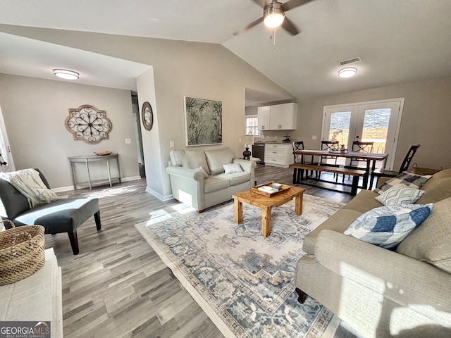 living room with ceiling fan, lofted ceiling, french doors, and light hardwood / wood-style flooring