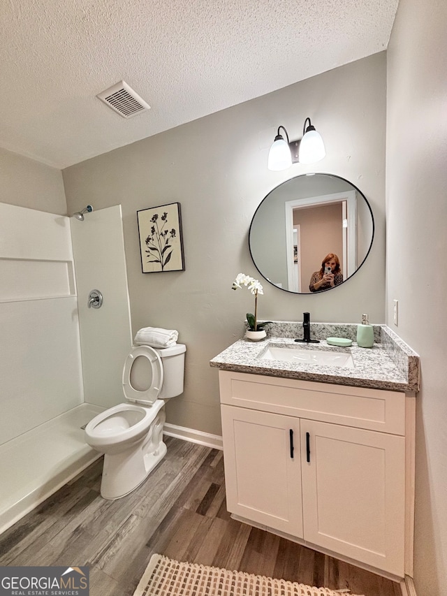 bathroom with hardwood / wood-style floors, vanity, a textured ceiling, and walk in shower