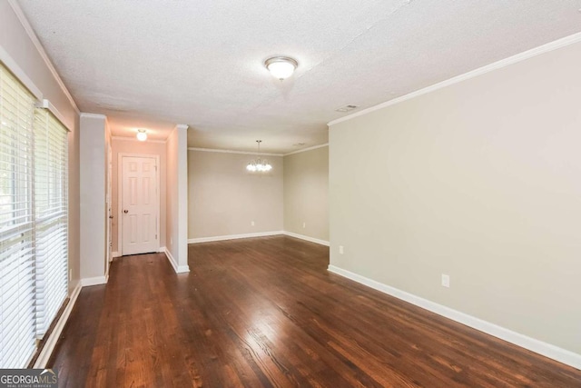 empty room featuring dark wood-type flooring, a textured ceiling, a notable chandelier, and ornamental molding