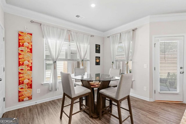 dining area featuring crown molding, hardwood / wood-style flooring, and plenty of natural light