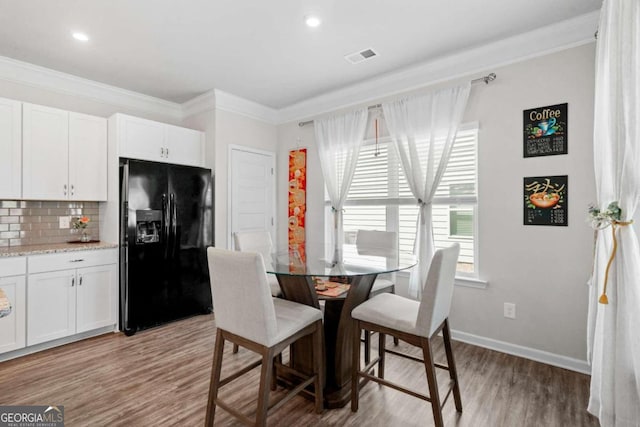 dining room featuring light wood-type flooring and crown molding