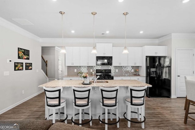 kitchen with white cabinetry, pendant lighting, black appliances, and an island with sink