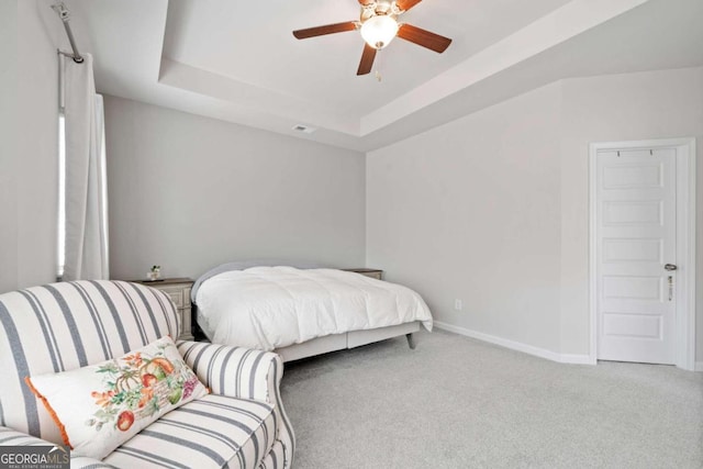 carpeted bedroom featuring ceiling fan and a raised ceiling