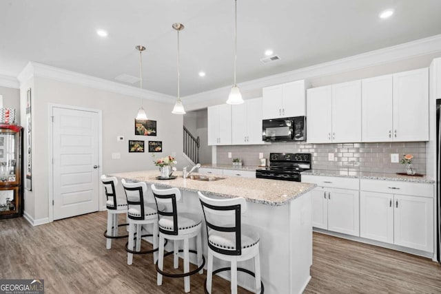 kitchen featuring black appliances, a kitchen island with sink, white cabinets, and pendant lighting