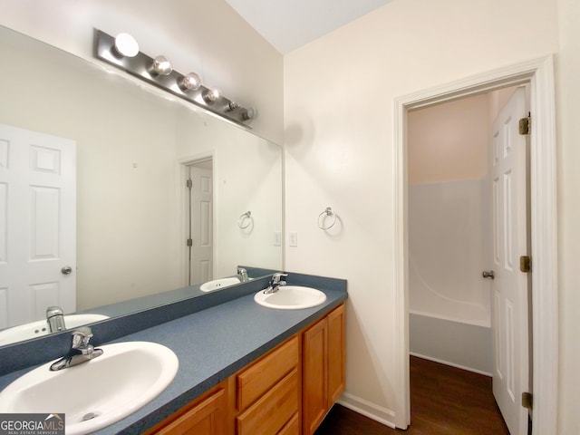 bathroom featuring wood-type flooring, a washtub, and vanity