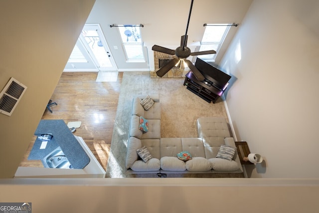 living room featuring a high ceiling, ceiling fan, and hardwood / wood-style flooring