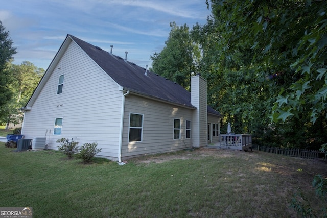 rear view of property featuring a yard, a wooden deck, and central air condition unit